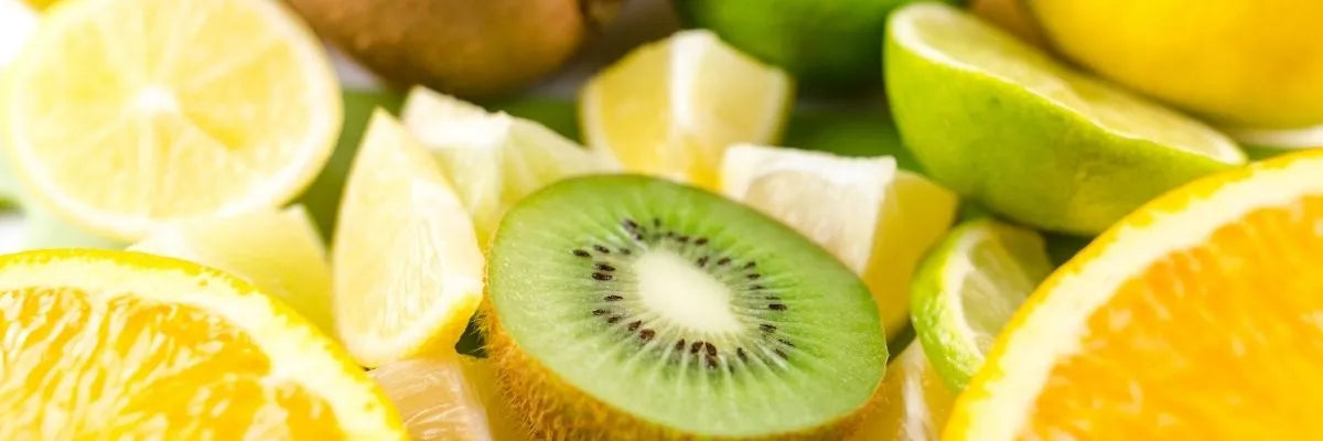 Close-up of sliced kiwi, lemon, lime, and orange fruit pieces on a green background