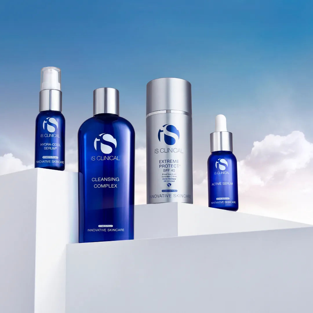 Four iS Clinical skincare products including Hydra-Cool Serum, Cleansing Complex, Extreme Protect SPF 40, and Active Serum on white platforms against blue sky