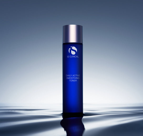iS Clinical Daily Active Smoothing Toner bottle standing on a rippled, reflective water surface in soft blue light