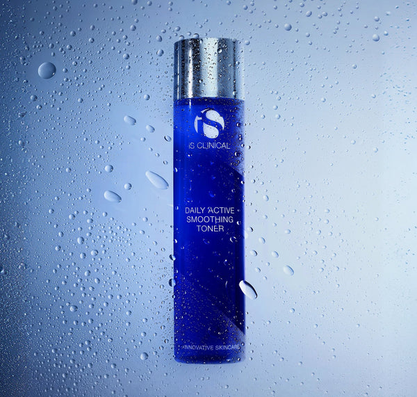 iS Clinical Daily Active Smoothing Toner bottle in front of misted glass beaded with water droplets
