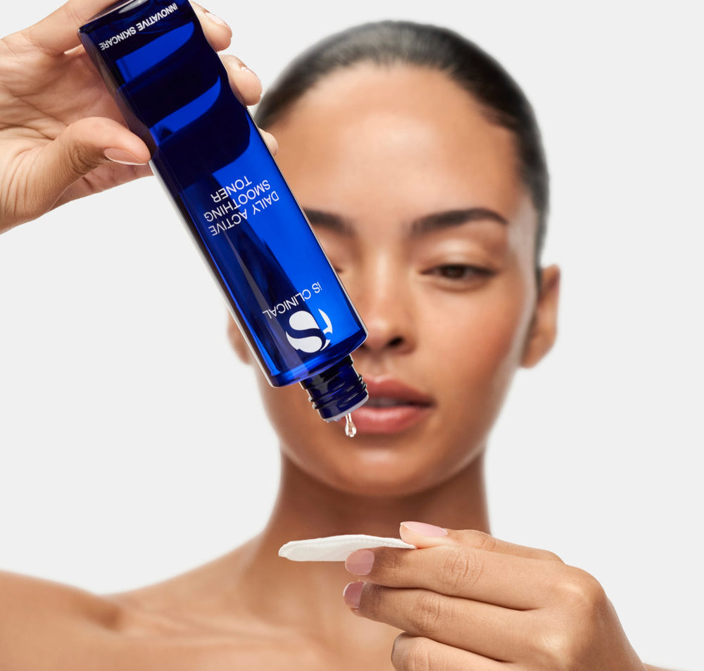 Woman dispensing iS Clinical Daily Active Smoothing Toner from the bottle onto a cotton pad