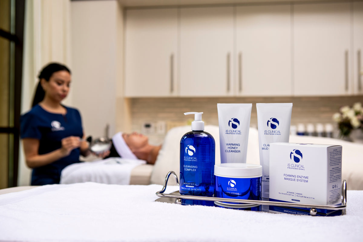 Tray with iS Clinical skincare products including Cleansing Complex and Warming Honey Cleanser in spa setting