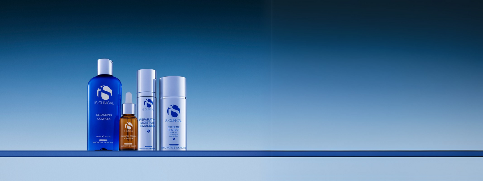 Four iS Clinical skincare products including Cleansing Complex, Pro-Heal Serum Advance+, Reparative Moisture Emulsion, and Extreme Protect SPF 30 on reflective surface