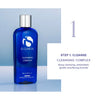Blue bottle of iS Clinical Cleansing Complex with silver cap on pale blue background