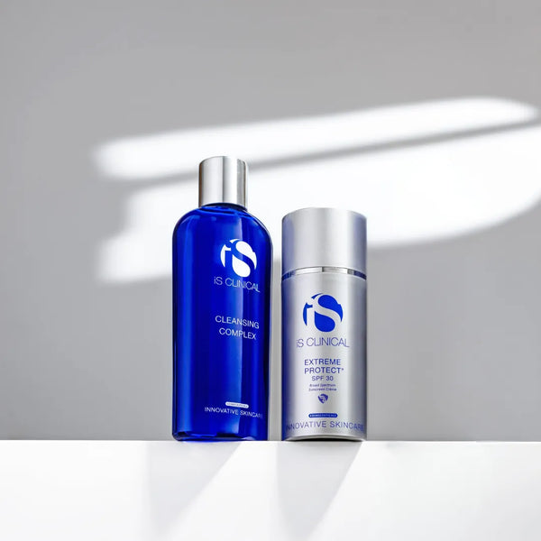 iS Clinical Cleansing Complex in blue bottle and Extreme Protect SPF 30 in silver pump bottle on white surface