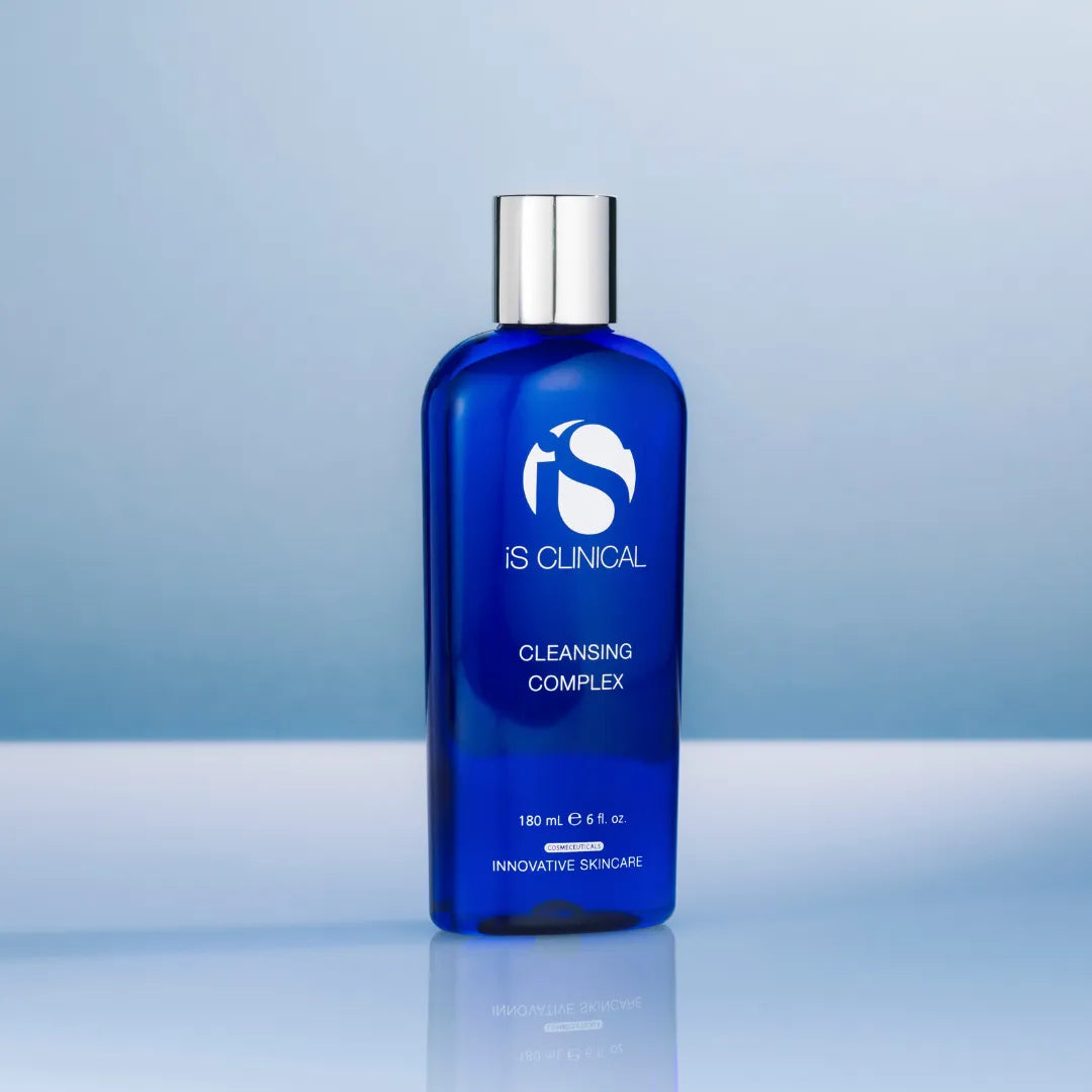 Blue bottle of iS Clinical Cleansing Complex with silver cap on reflective surface