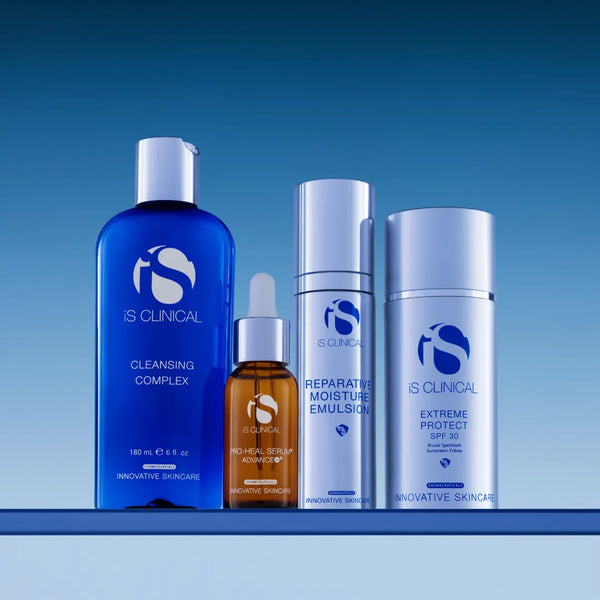 iS Clinical skincare products including Cleansing Complex, Pro-Heal Serum Advance+, Reparative Moisture Emulsion, and Extreme Protect SPF 30 on a blue surface