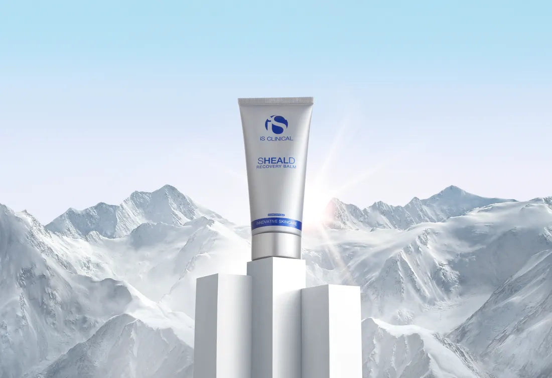 iS Clinical Sheald Recovery Balm tube on white pedestal with snowy mountain background