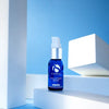 Blue glass bottle of iS Clinical Poly-Vitamin Serum with white pump on white geometric blocks