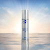 Silver bottle of iS Clinical Reparative Moisture Emulsion 50g standing on reflective water surface with sunrise background