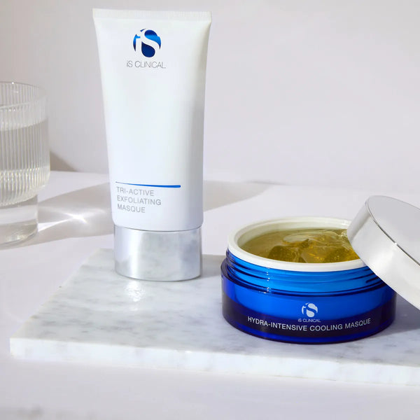 iS Clinical Tri-Active Exfoliating Masque tube and open blue jar of Hydra-Intensive Cooling Masque on marble slab