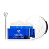 Open blue jar of iS Clinical Youth Intensive Creme with white cream and silver applicator spoon on white background
