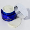 Open blue jar of iS Clinical Youth Intensive Crème with silver lid and cream texture spread on white surface