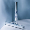 Two silver cylindrical tubes of iS Clinical Youth Lip Elixir on a curved white and blue surface